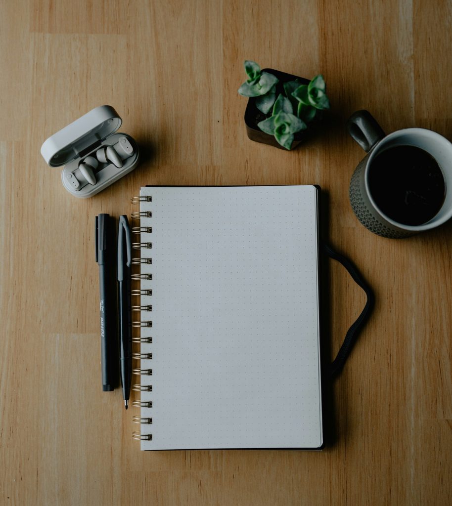 Escritorio con cuaderno, bolígrafos y una taza de café